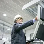 Serious mature male plant engineer operating industrial machine pushing buttons control panel holding tablet copy 150x150